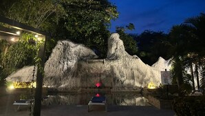 A nighttime outdoor area with a rock formation, a small pool, and a seating area. - Hotel Diuwak (Bahía Ballena)