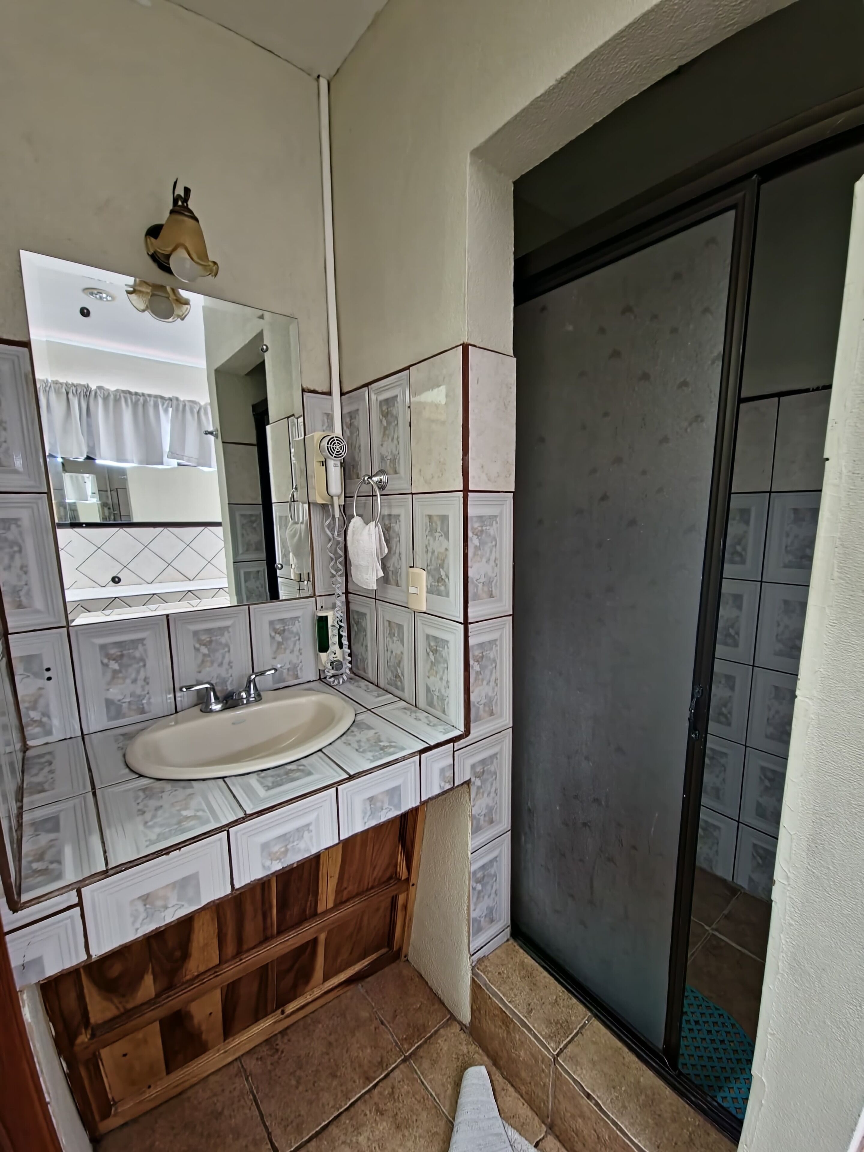 A bathroom with a sink, mirror, and shower.
