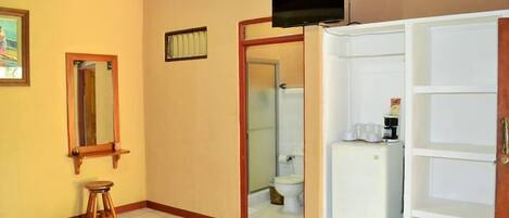 A hotel room with a bed, a television, a wardrobe, and a bathroom visible through an open door.