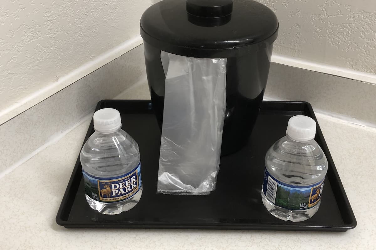 Eine schwarze Ablagefläche mit zwei Deer Park Wasserflaschen und einer transparenten Plastiktüte auf einer Arbeitsplatte.