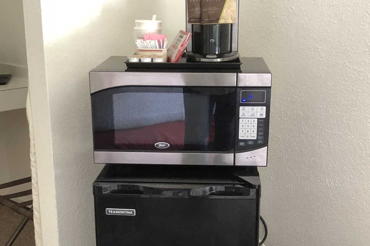 Ein schwarzer Kühlschrank mit einer Edelstahl-Mikrowelle darüber.