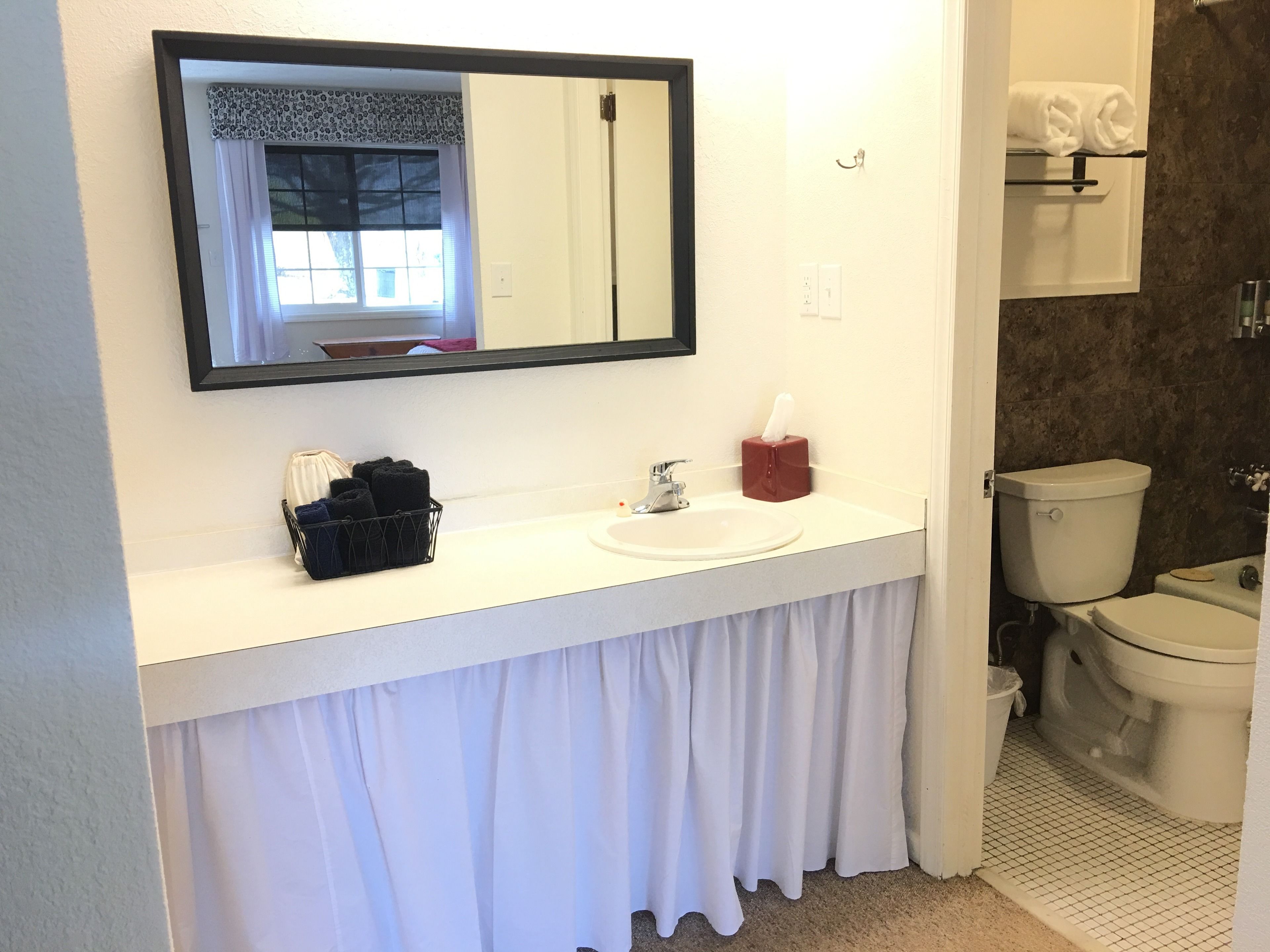 A bathroom with a white sink, a mirror, a toilet, and a towel rack.