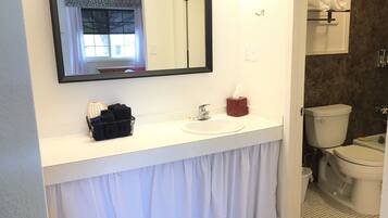 A bathroom with a white sink, a mirror, a toilet, and a towel rack.