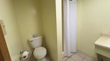 A bathroom with a toilet, a shower curtain, and a sink.
