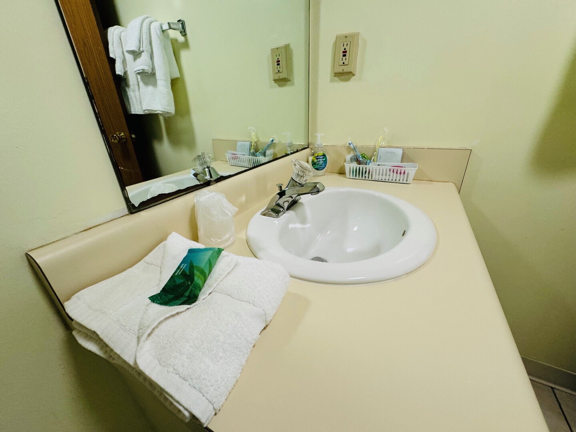 A hotel bathroom with a sink, mirror, and toiletries.