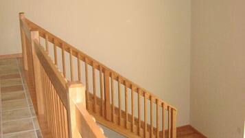 A wooden staircase with a tiled floor leading to a room with a wooden table and chairs.