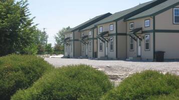 A row of two-story buildings with a gravel driveway and green landscaping.