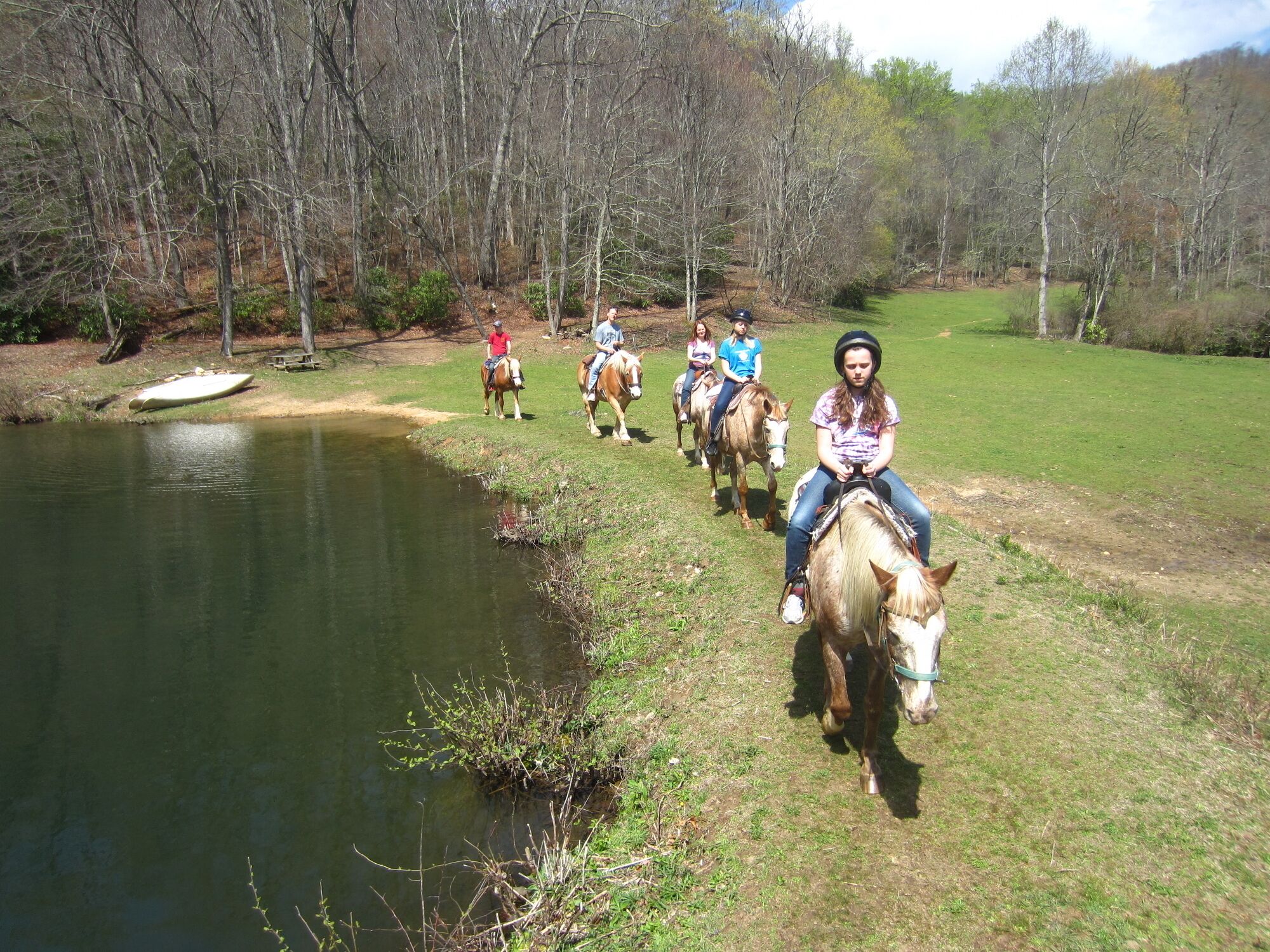 Un grupo de personas montando a caballo a lo largo de la orilla de un río.