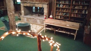 A cozy room with a fireplace, a wooden bench, and a bookshelf. - Arrowmont Stables & Cabins (Cullowhee)