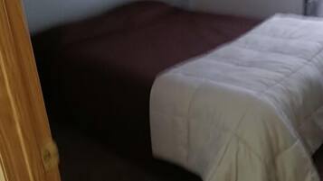 Un dormitorio con cama, cabecero oscuro y pared de color claro.