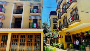 A building with balconies adorned with Mexican flags, a sign for 'Fancín International Suites', and a restaurant named 'RIVIVIA EXCITO' with outdoor seating. - Cancun International Suites (Cancun)