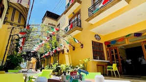 A courtyard with tables set for dining, surrounded by yellow buildings with balconies. - Cancun International Suites (Cancun)