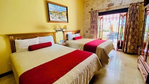 A hotel room with two beds, a painting on the wall, and a view of the outside through a glass door. - Cancun International Suites (Cancun)