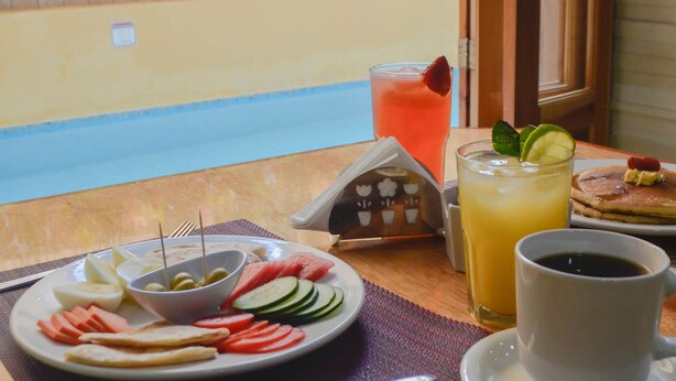 A breakfast table with a plate of food, a glass of juice, and a cup of coffee. - Cancun International Suites (Cancun)