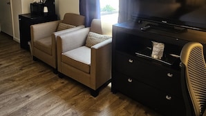 A living room with a sofa, a TV, a small table, and a window with curtains.