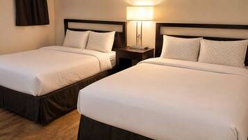 Two twin beds with matching headboards and footboards, a bedside table with a lamp, and a wooden floor.