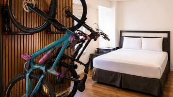 Una habitación con una cama, una mesita de noche, un soporte para bicicleta en la pared y un revestimiento de listones de madera.