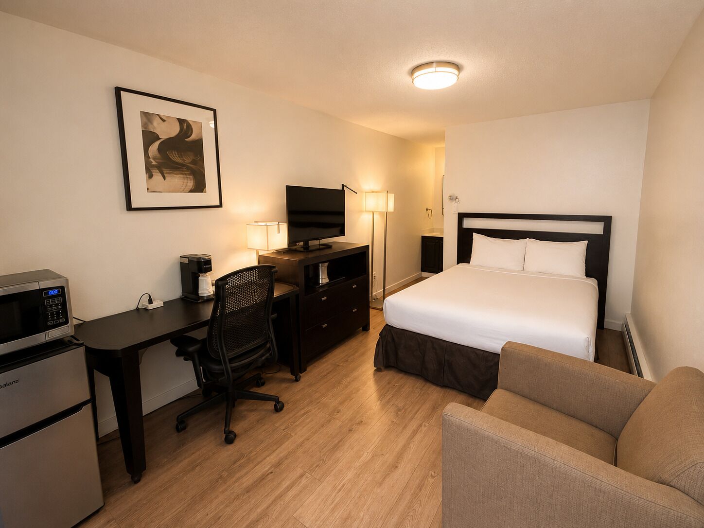 Habitación de hotel con cama, escritorio, silla y televisión.
