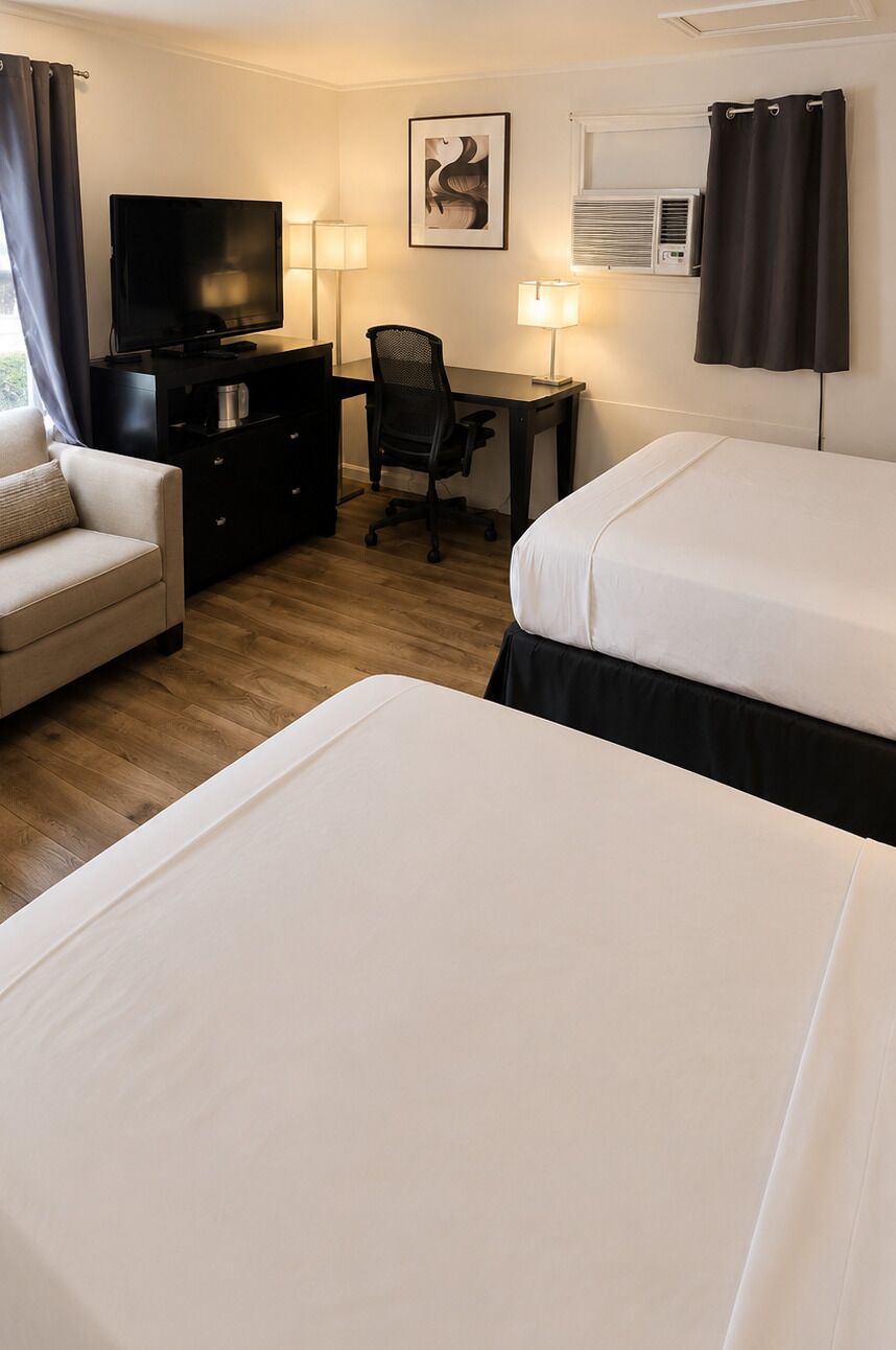 A hotel room with two beds, a desk with a chair, a television, a desk lamp, and a picture on the wall.