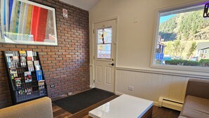 A cozy lobby with a brick wall, a white reception desk, and a window offering a view of a hillside.