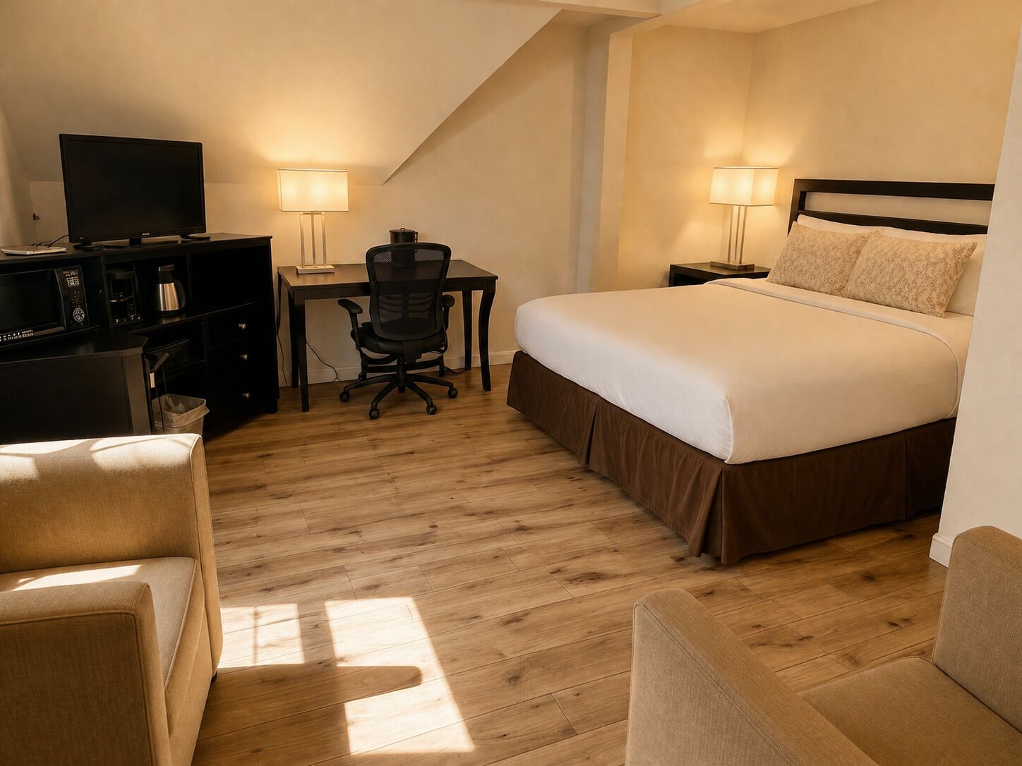 Une chambre d’hôtel équipée d’un lit, d’un bureau, d’une chaise, d’une télévision et de lampes.