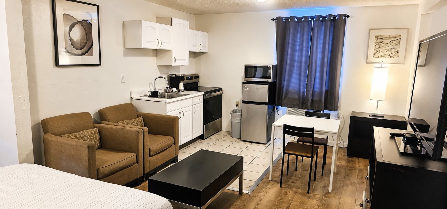 A compact living space with a kitchenette, a sofa, a dining table, and a TV.
