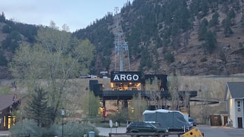 A mountain landscape with a building labeled 'ARGO' and a green SUV parked in front.