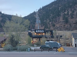 A mountain landscape with a building labeled 'ARGO' and a green SUV parked in front.