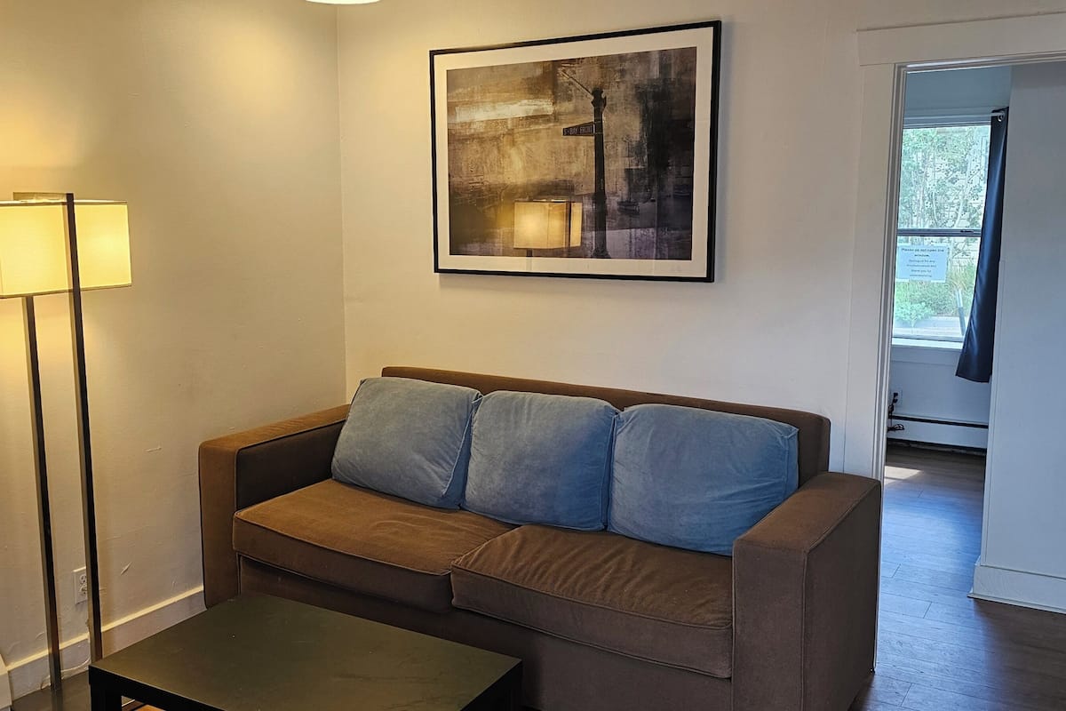 A living room with a sofa, a floor lamp, and a framed picture on the wall.