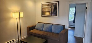 A living room with a sofa, a floor lamp, and a framed picture on the wall. - H & H Motor Lodge (Idaho Springs)