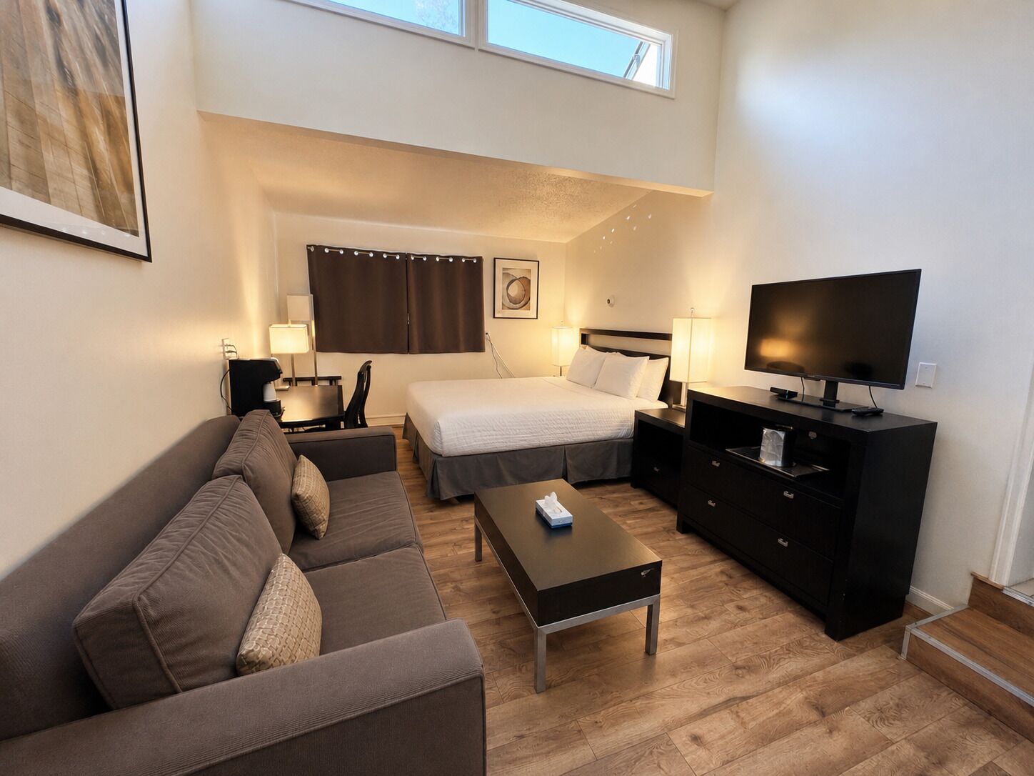 Une chambre d’hôtel avec un lit, un canapé, une télévision et un bureau.