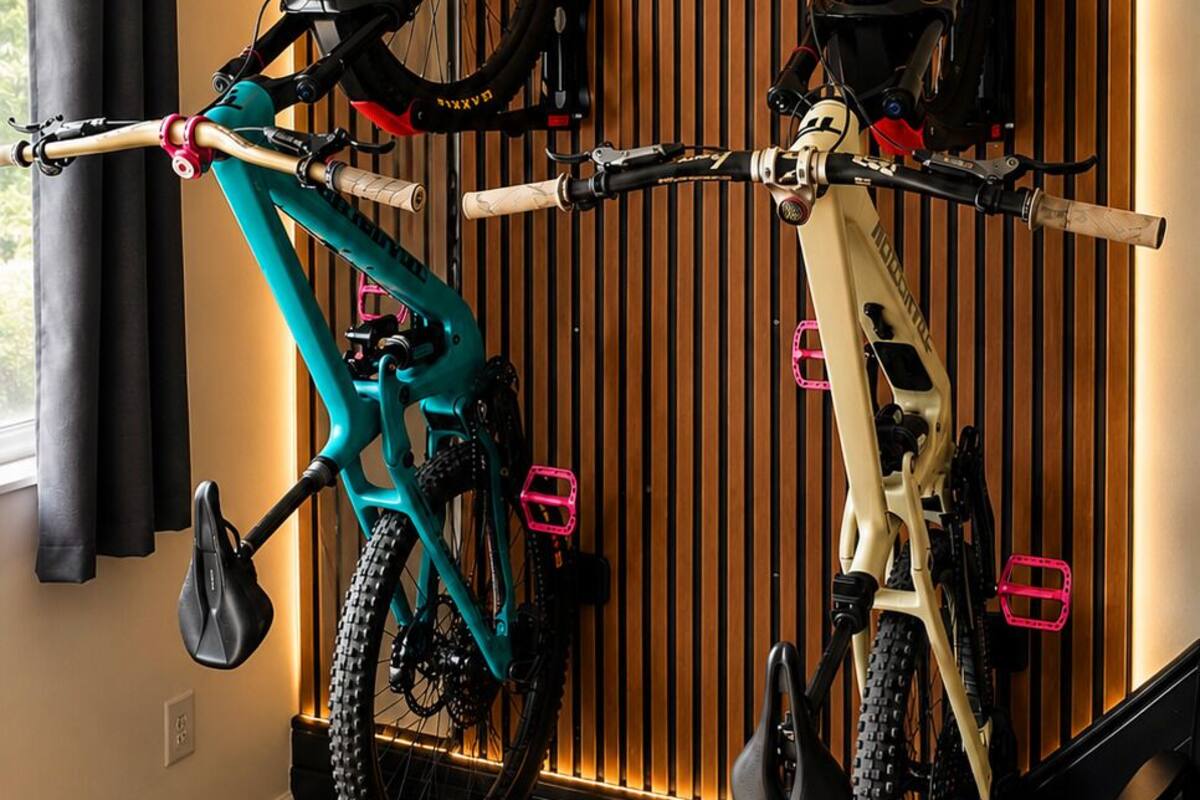A room with a wooden slat wall, two bicycles mounted on a rack, a black mat on the floor, and a black chair.