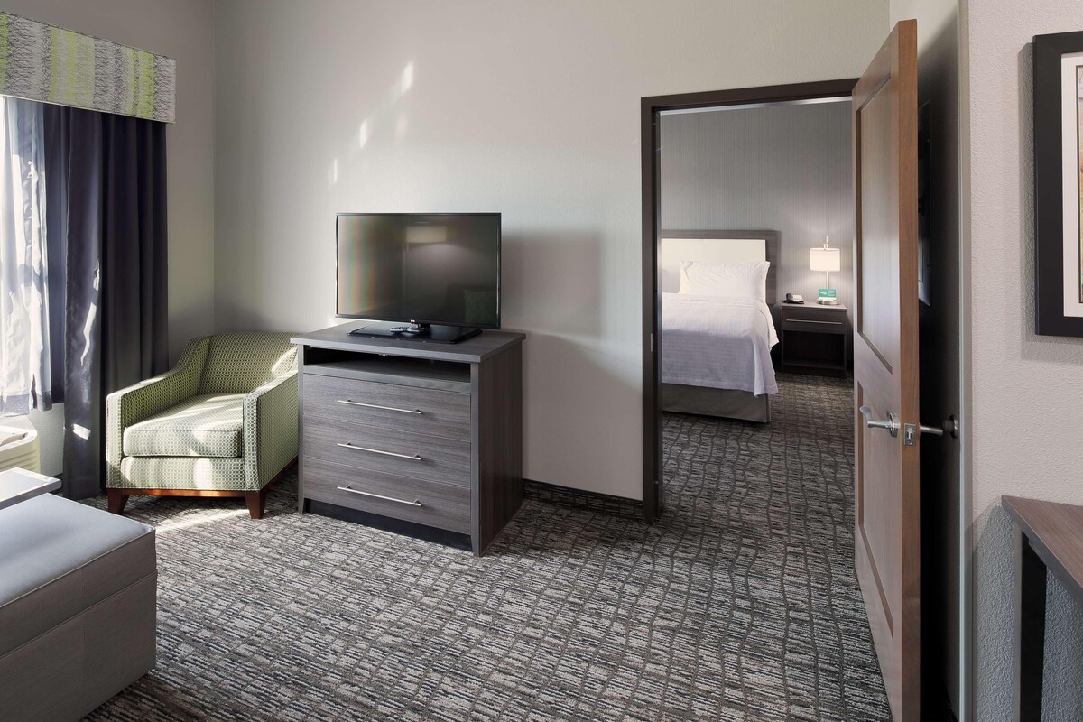 A hotel room with a bed, a desk with a television, a chair, and a wardrobe.