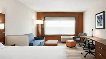 Een hotelkamer met een groot bed, een bureau, een stoel, een bank en een raam met uitzicht.