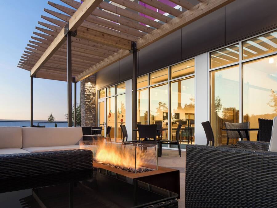 An outdoor seating area with a fire feature, modern furniture, and large windows offering views of the sea.