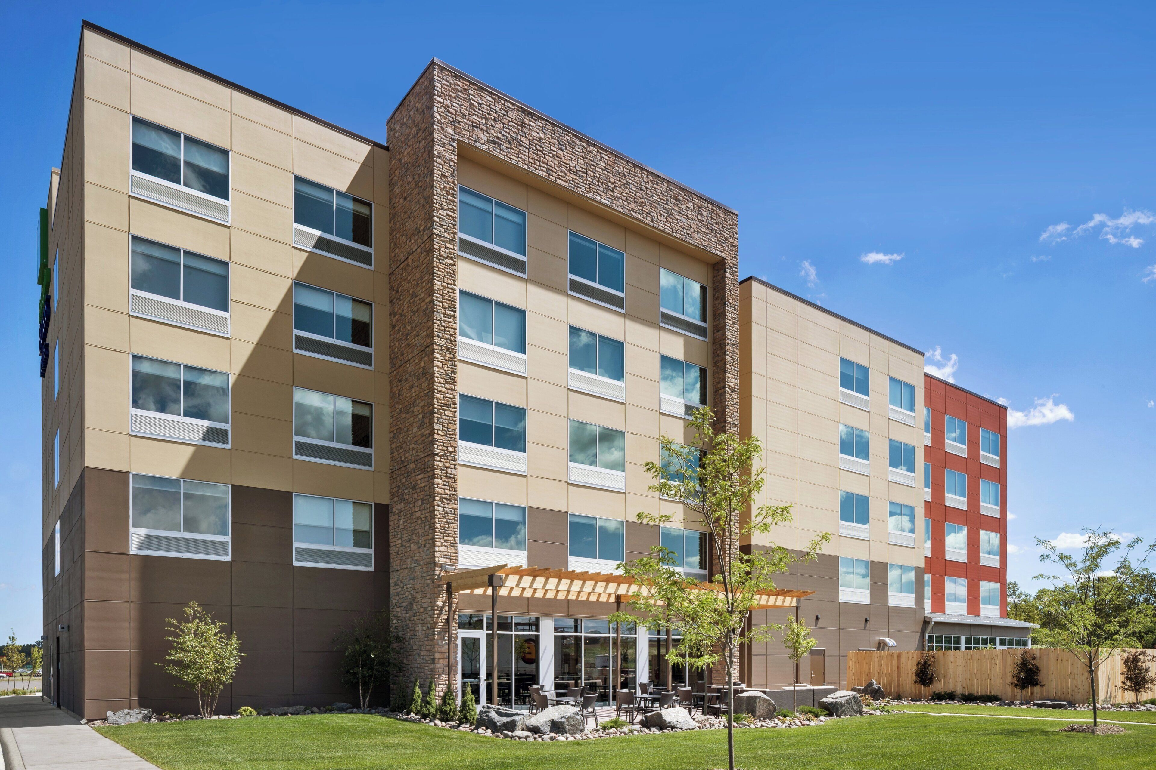 A multi-story hotel with a central courtyard, outdoor seating, and a mix of stone and panel exteriors.