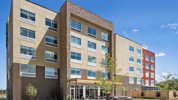 A multi-story hotel with a central courtyard, outdoor seating, and a mix of stone and panel exteriors.