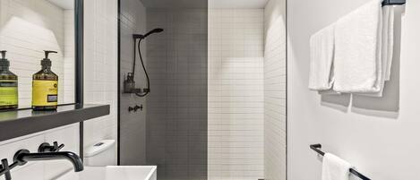Un baño moderno con lavamanos blanco, grifo negro y zona de ducha.