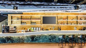 A bar area with a marble counter, multiple shelves of bottles, and bar stools. - Peppers Southern Cross Melbourne (Docklands)