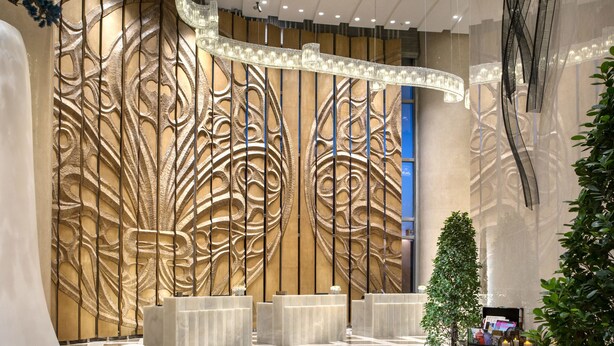 Eine geräumige Lobby mit Schachbrettmuster-Boden, einer Rezeption und einer Wand mit Baumdekor.
