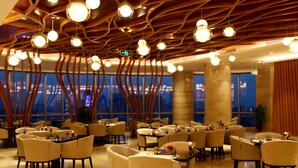 Een modern restaurant met een opvallend plafondontwerp, grote ramen en comfortabele zitplaatsen.