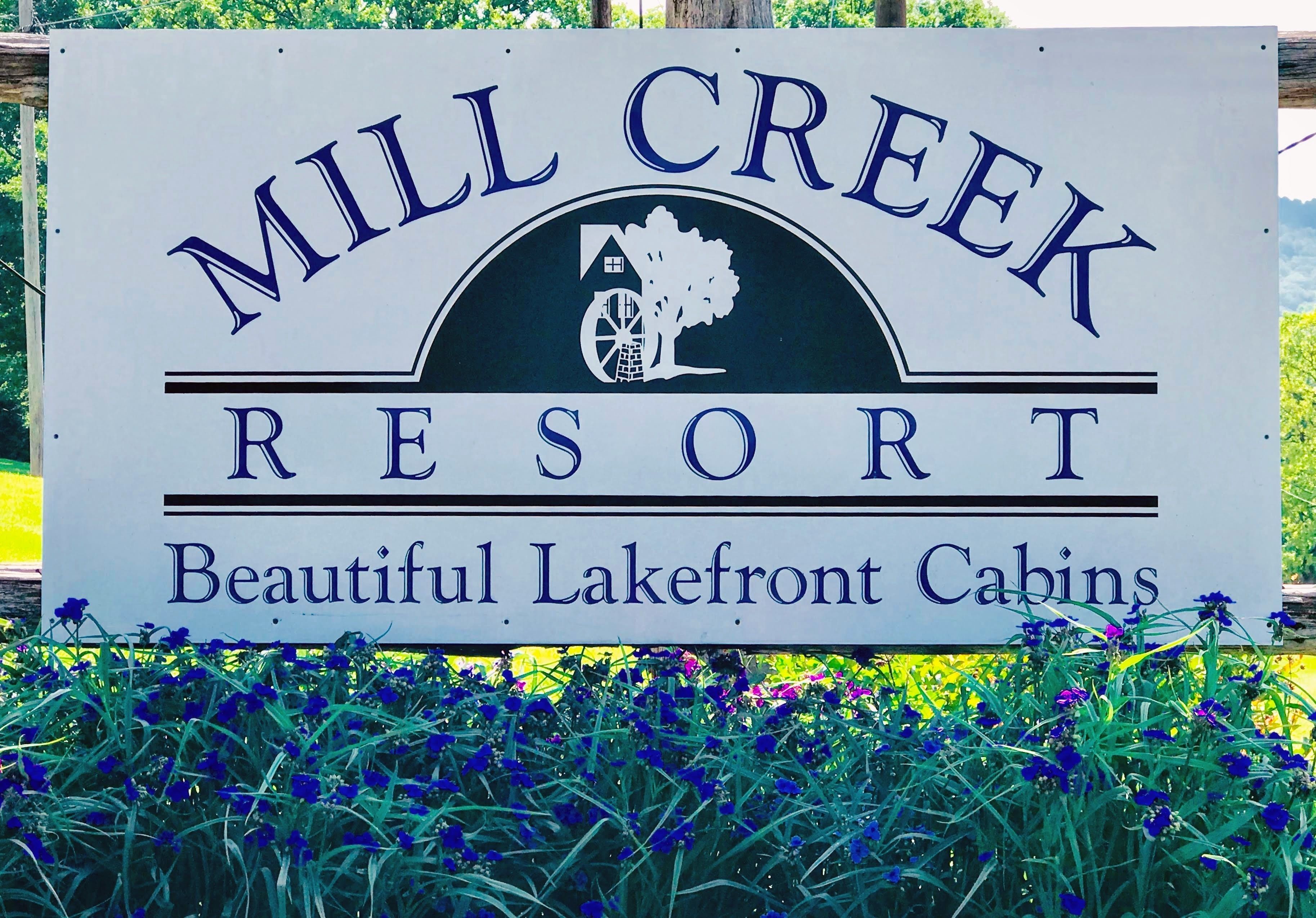 Une pancarte indiquant le « Mill Creek Resort » et faisant la publicité de « magnifiques chalets situés au bord du lac ».
