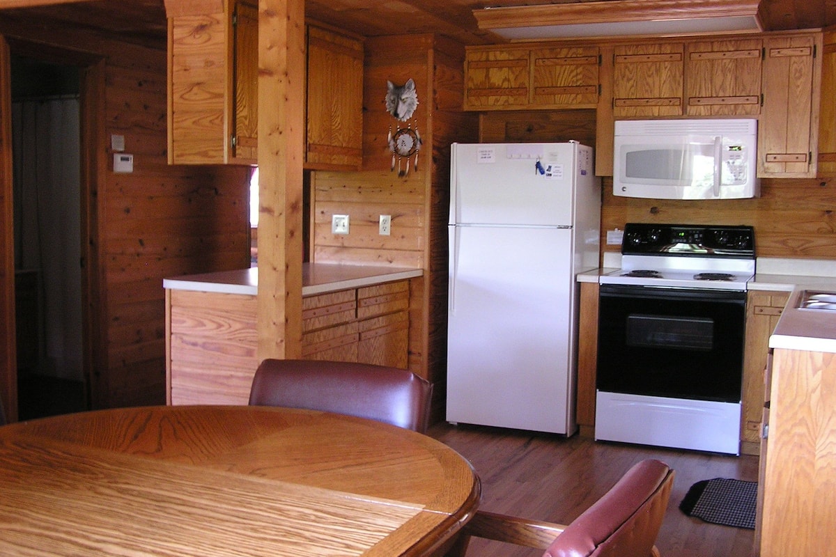 Une cuisine de taille réduite, dotée de meubles de rangement en bois, d’un réfrigérateur, d’un four à micro-ondes et d’une cuisinière.
