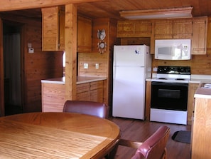A compact kitchen with wooden cabinets, a refrigerator, a microwave, and a stove. - Mill Creek Resort on Table Rock Lake (Lampe)