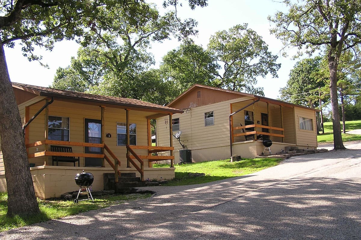 Deux cabanes en bois dotées de vérandas, d’un barbecue et d’une allée en gravier.