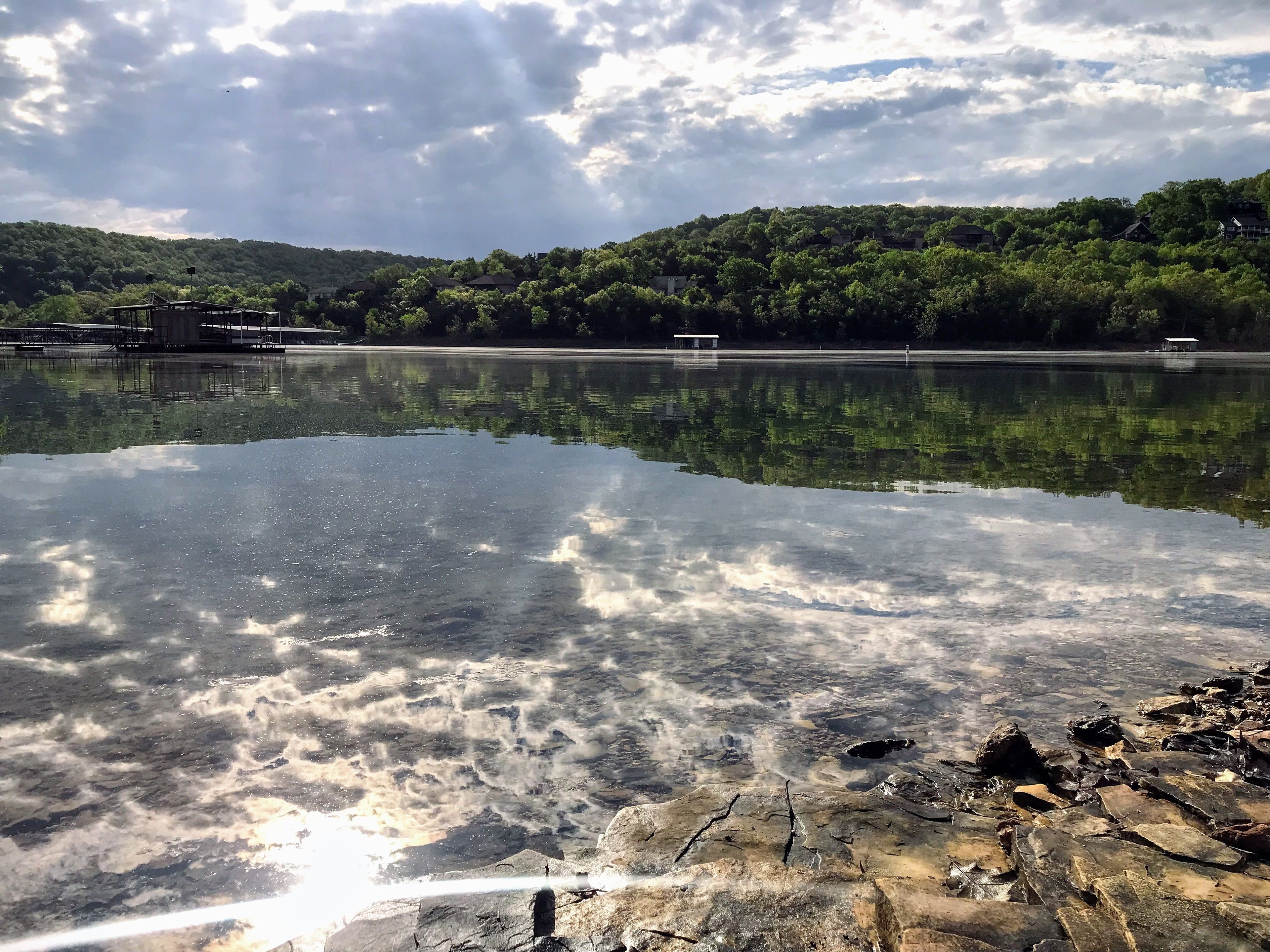 Un lago tranquilo con reflejos nítidos del cielo y árboles circundantes.
