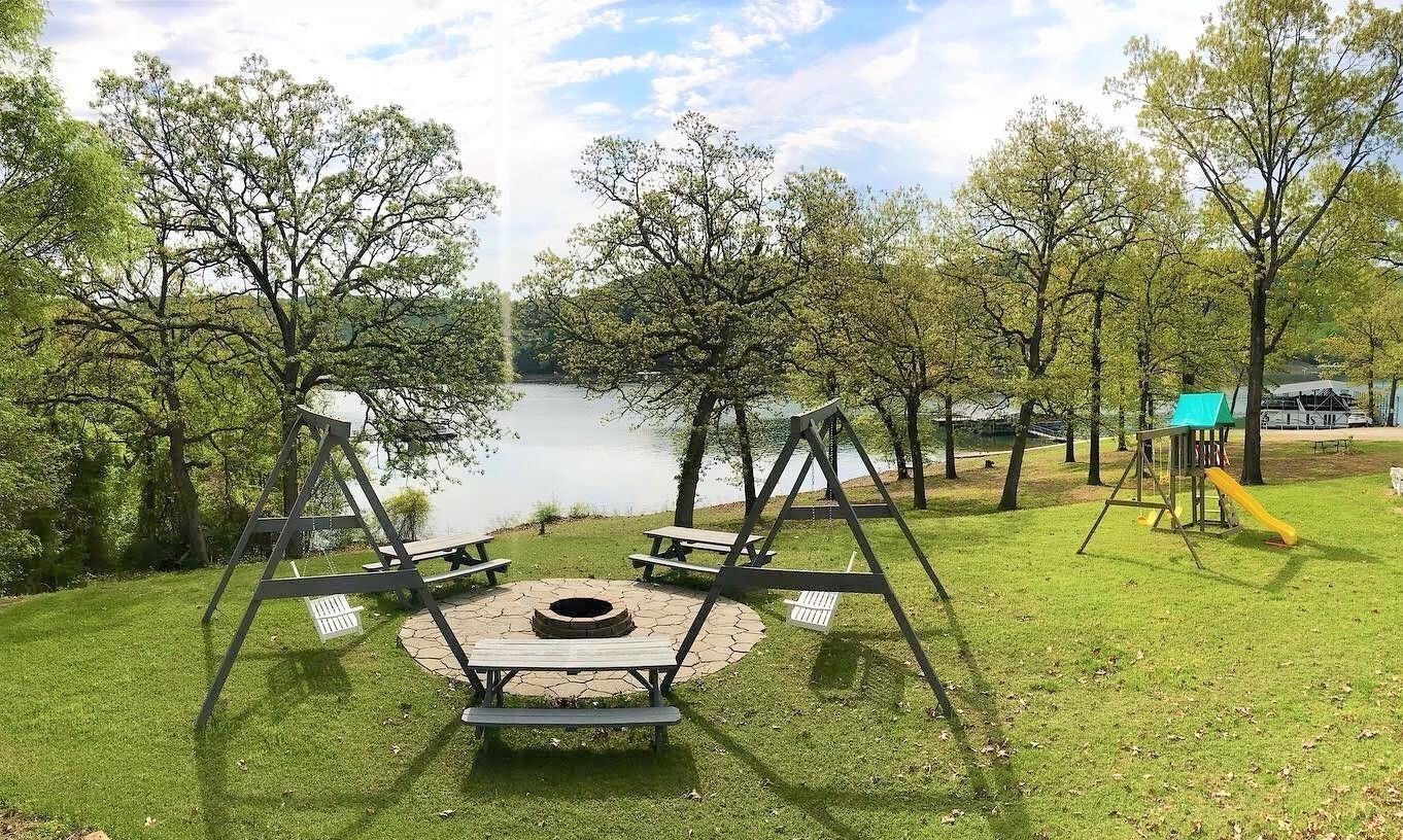 A park with picnic tables, a swing set, and a fire pit.