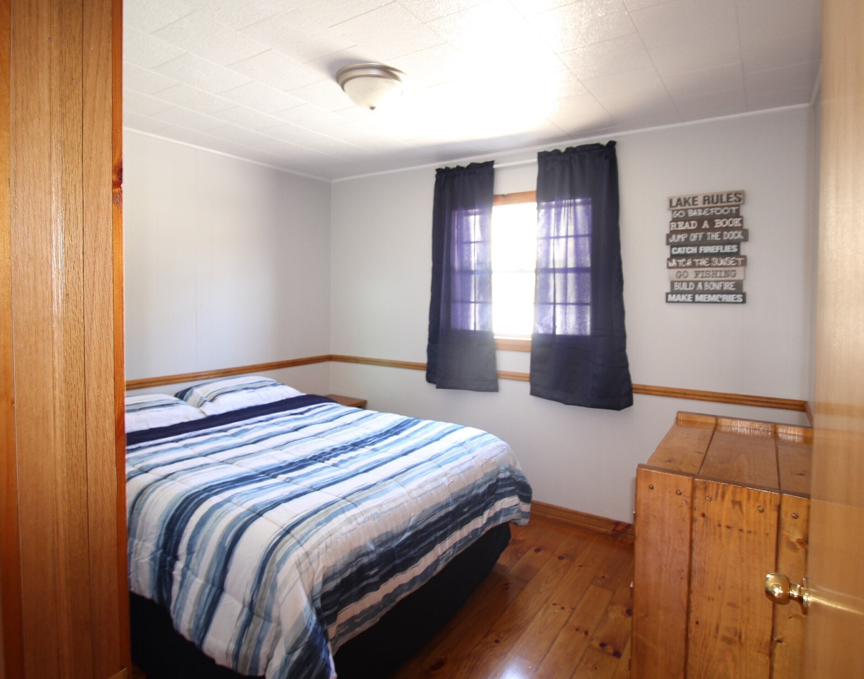 Un dormitorio con cama, armario de madera y una pared con una lista de normas.