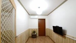 Un pasillo estrecho con paneles de madera, una puerta al final y una pequeña mesa con una planta.