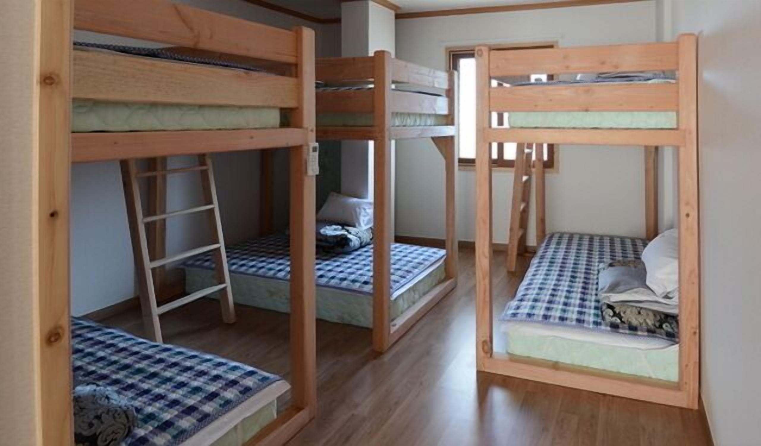 Una habitación con tres literas, cada una con una escalera, y un escritorio pequeño en el centro.